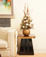 Brass Corner Sofa with a white couch and a Tower End Table holding a bronze vase with flowers in a chic living room.