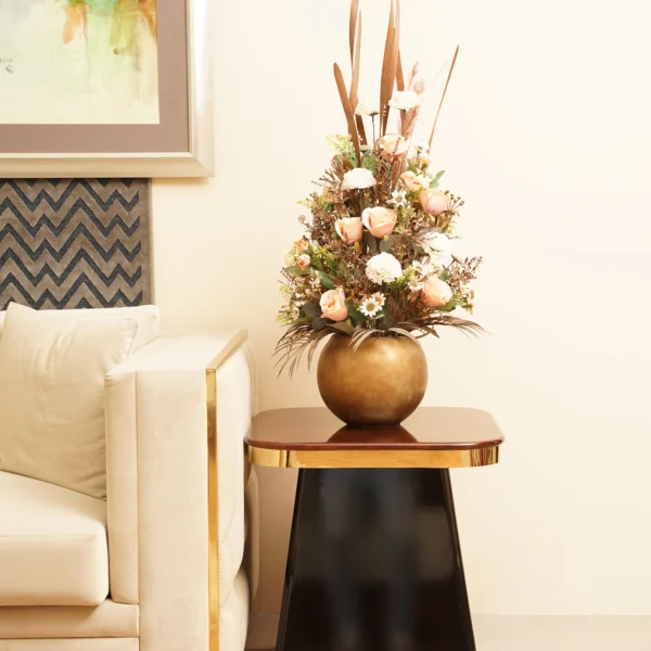 Brass Corner Sofa with a white couch and a Tower End Table holding a bronze vase with flowers in a chic living room.